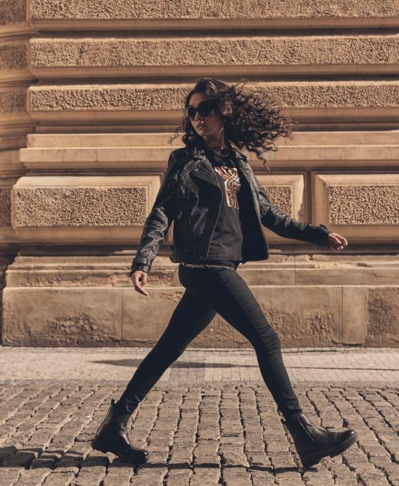 Woman in a leather jacket looking over her shoulder as she is walking